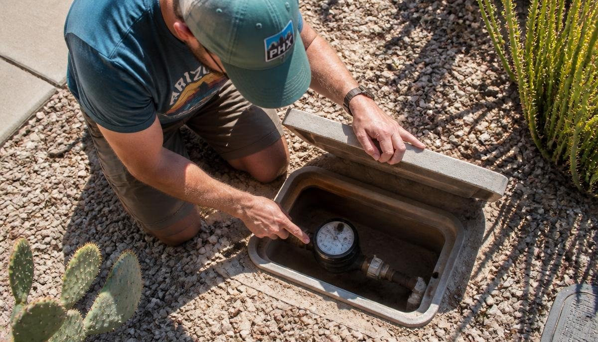 A homeowner checking a digital water meter for a leak indicator while the house is quiet